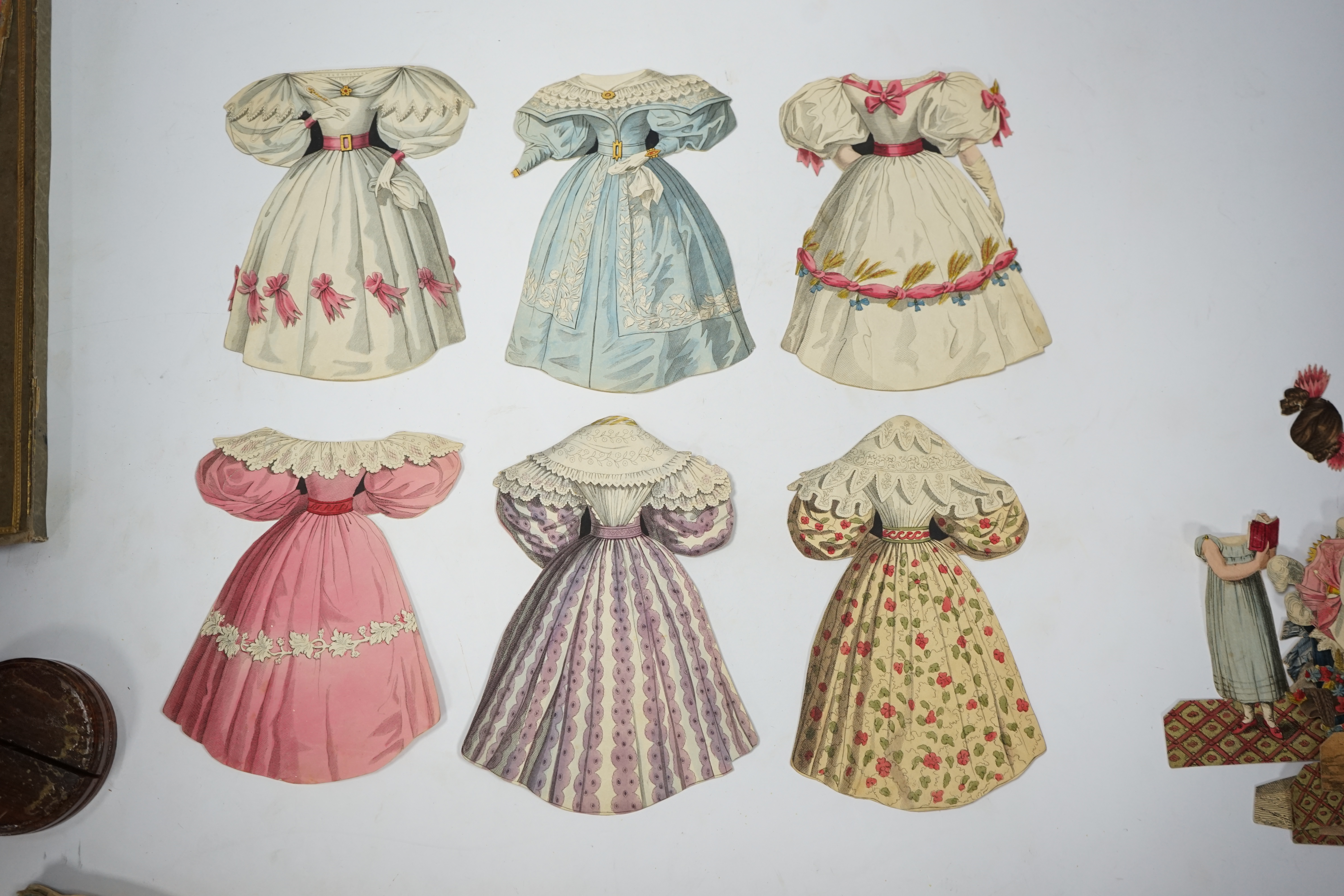 An early 19th century boxed Rudolph Ackermann La Poupee-Modele paper doll set, comprising of a double sided doll in lingerie with mahogany stand, six double sided gowns and four bonnets, together with eight similar figur